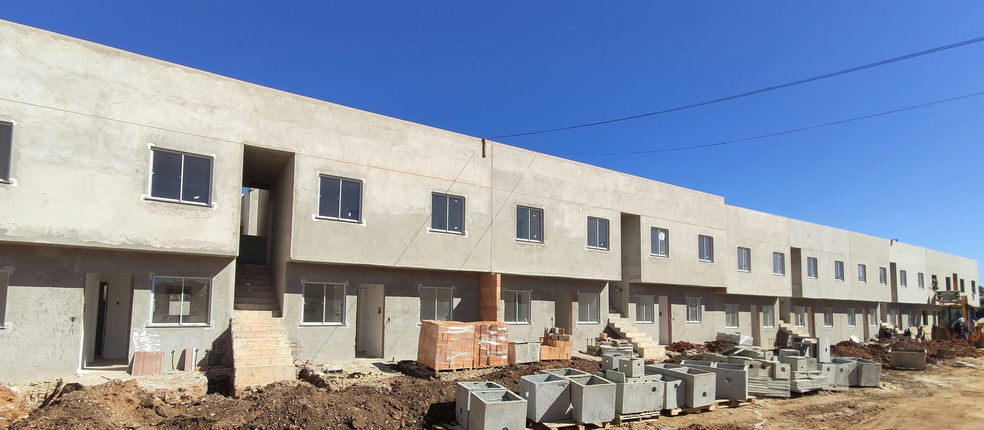 Empreendimento residencial em fase de acabamento, com caixas de inspeção e material no canteiro