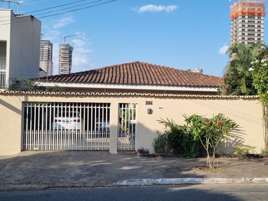 Mesma quadra, dois mercados: residência t&eacute;rrea e torre em constru&ccedil;&atilde;o ao fundo. O potencial construtivo do lote costuma valer mais que a casa que est&aacute; sobre ele.