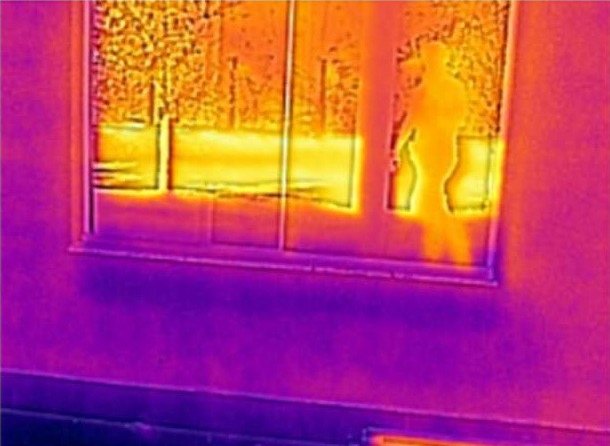 O contraste térmico no contorno da esquadria indica falha de vedação, causa frequente de mancha atribuída a infiltração de fachada.
